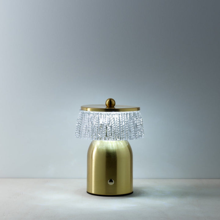Gold table lamp with crystal shade on a gray background