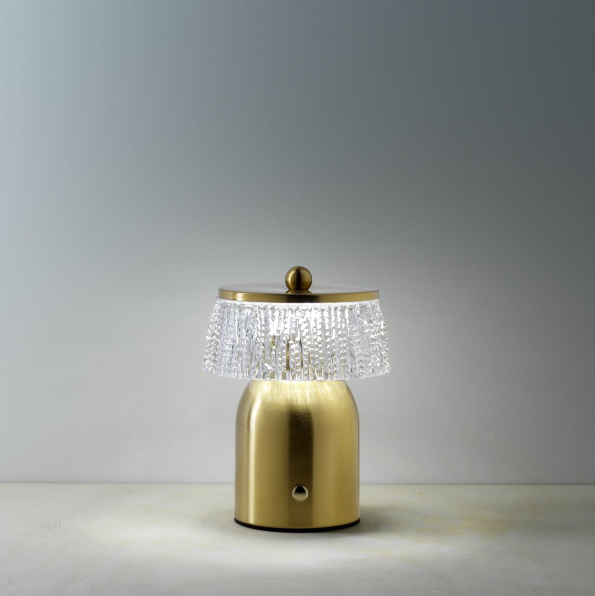 Gold table lamp with crystal shade on a gray background