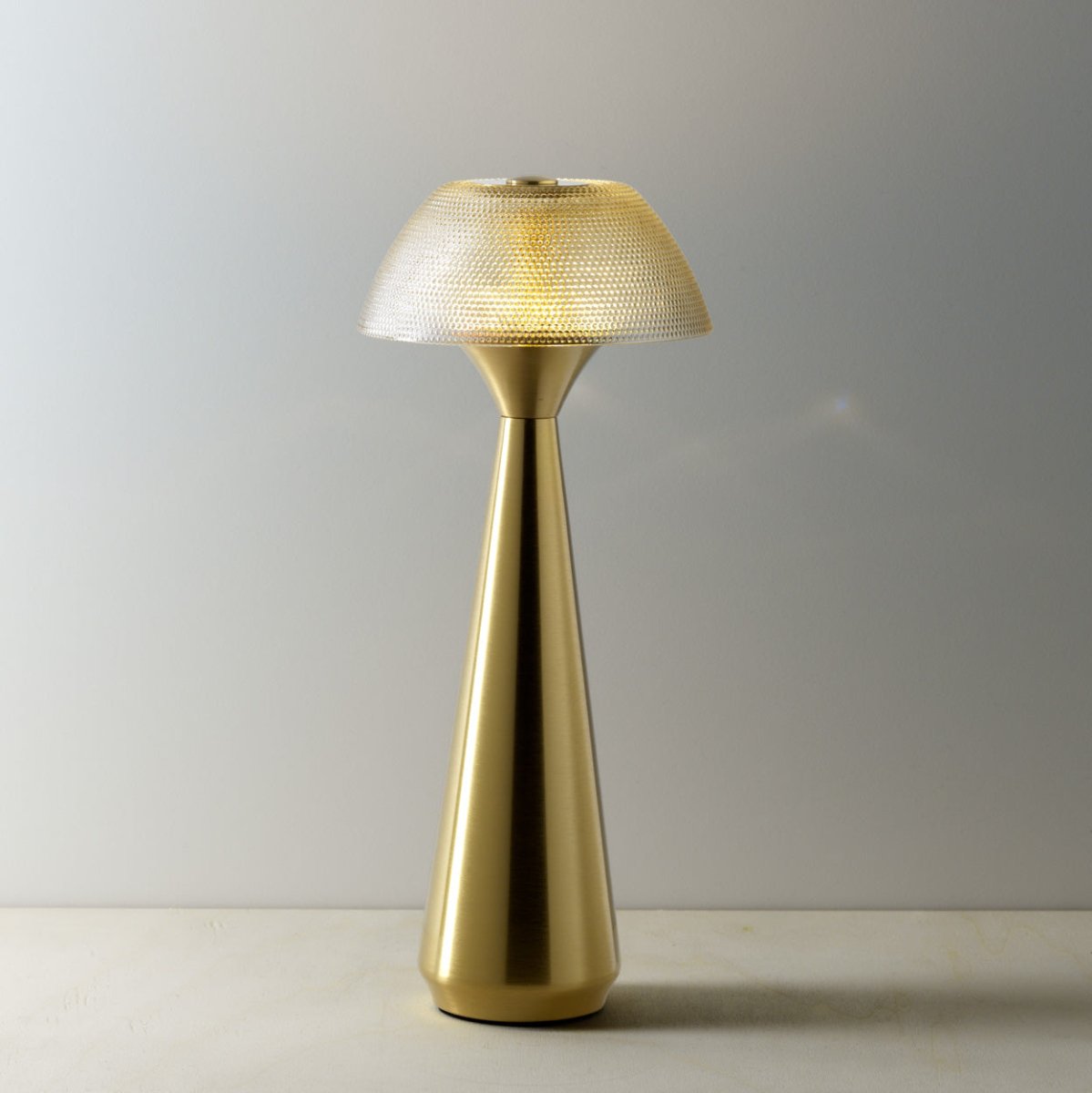 Gold table lamp with textured shade on a plain background