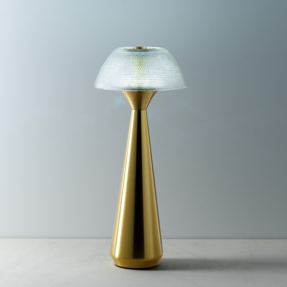 Gold table lamp with a textured shade on a gray background