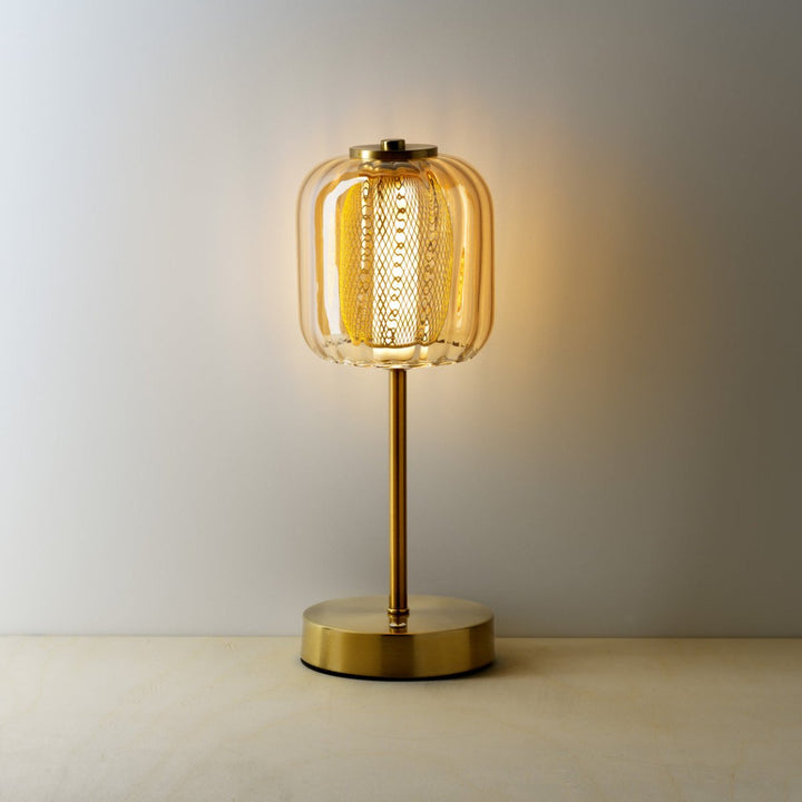 Gold table lamp with a textured glass shade on a neutral background