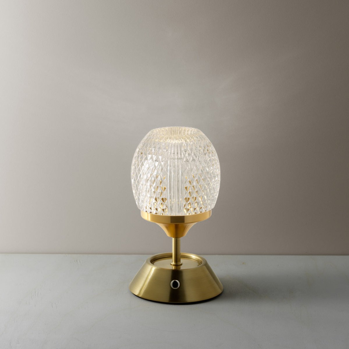 Table lamp with textured glass shade and gold base on a neutral background