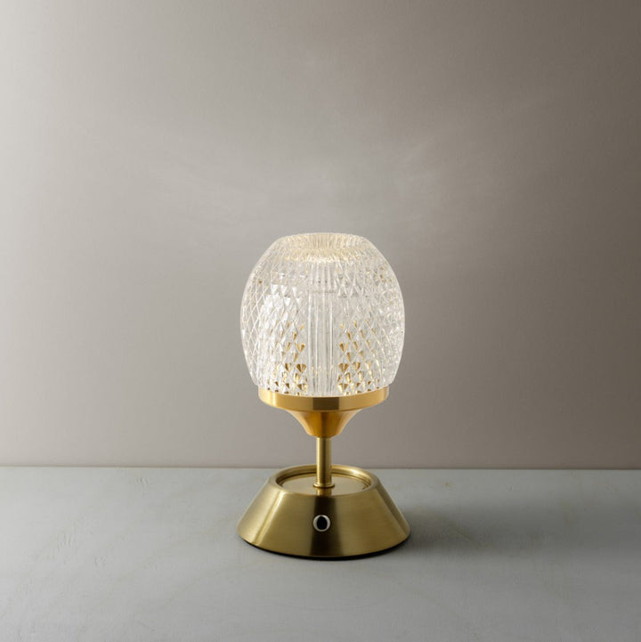 Table lamp with textured glass shade and gold base on a neutral background