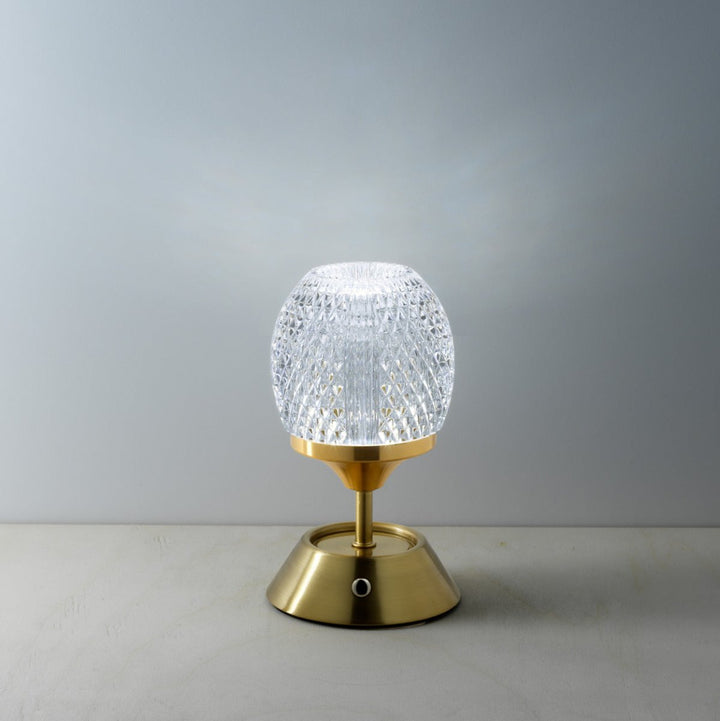 Small table lamp with a textured glass shade and gold base on a neutral background