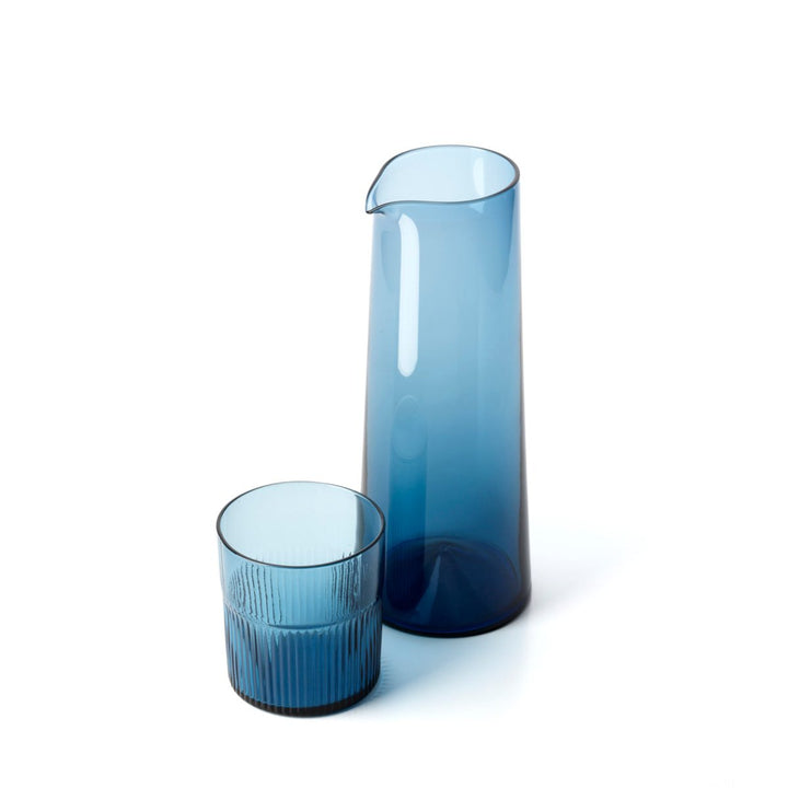 Two blue glass pieces, a tall cylindrical vase and a shorter round glass, on a white background.
