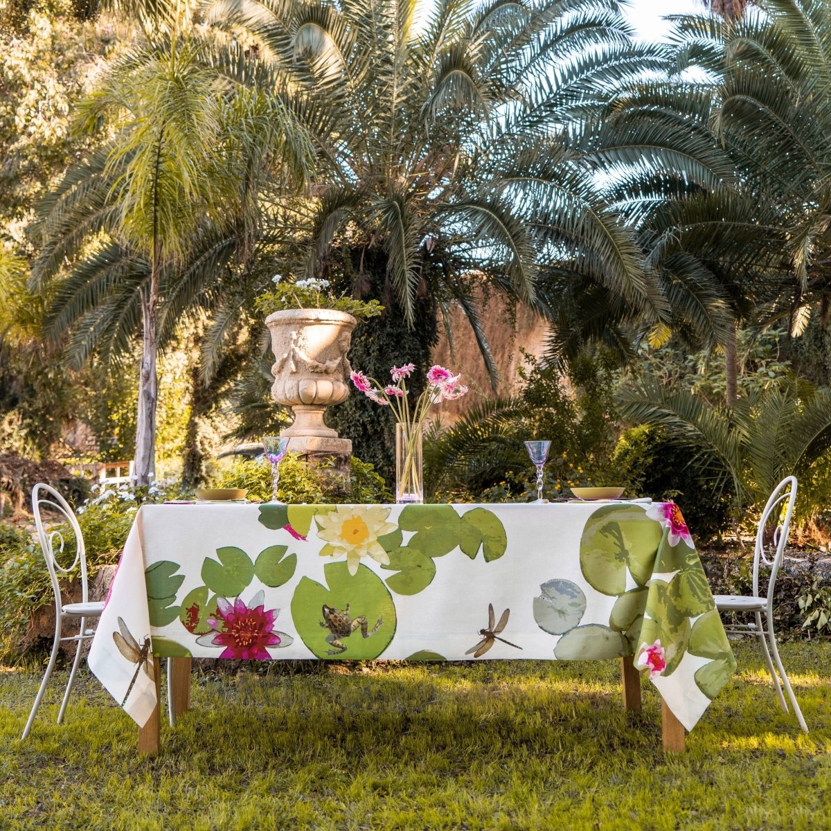 Table with a floral tablecloth in a garden setting with palm trees.