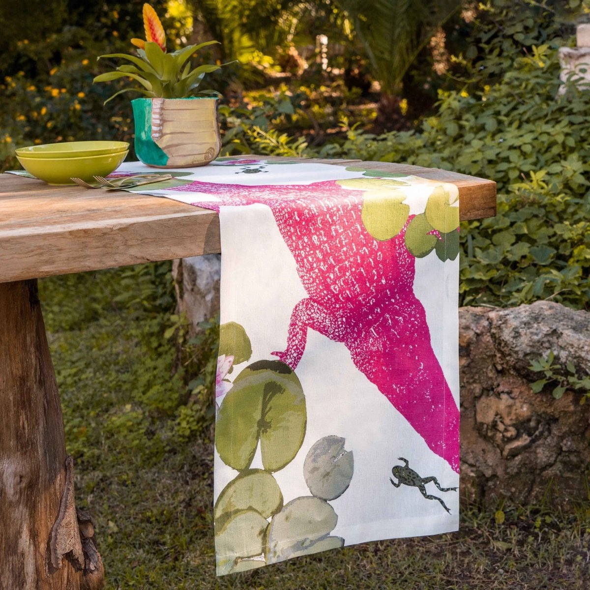Table with a decorative tablecloth featuring a pink lizard design in a garden setting