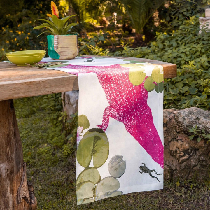 Table with a decorative tablecloth featuring a pink lizard design in a garden setting