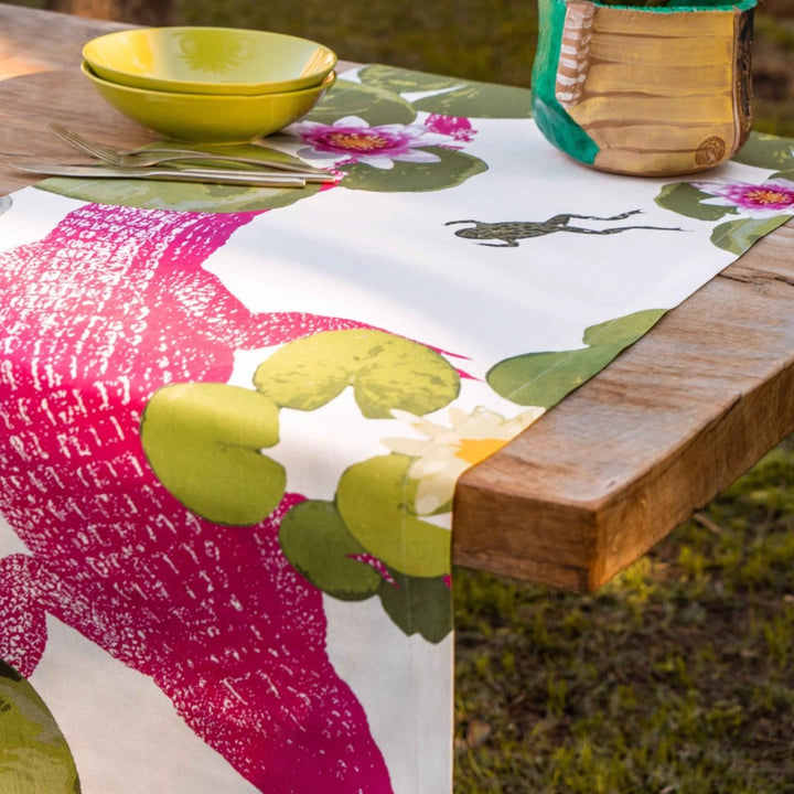 Table setting with a colorful floral tablecloth on a wooden table outdoors.