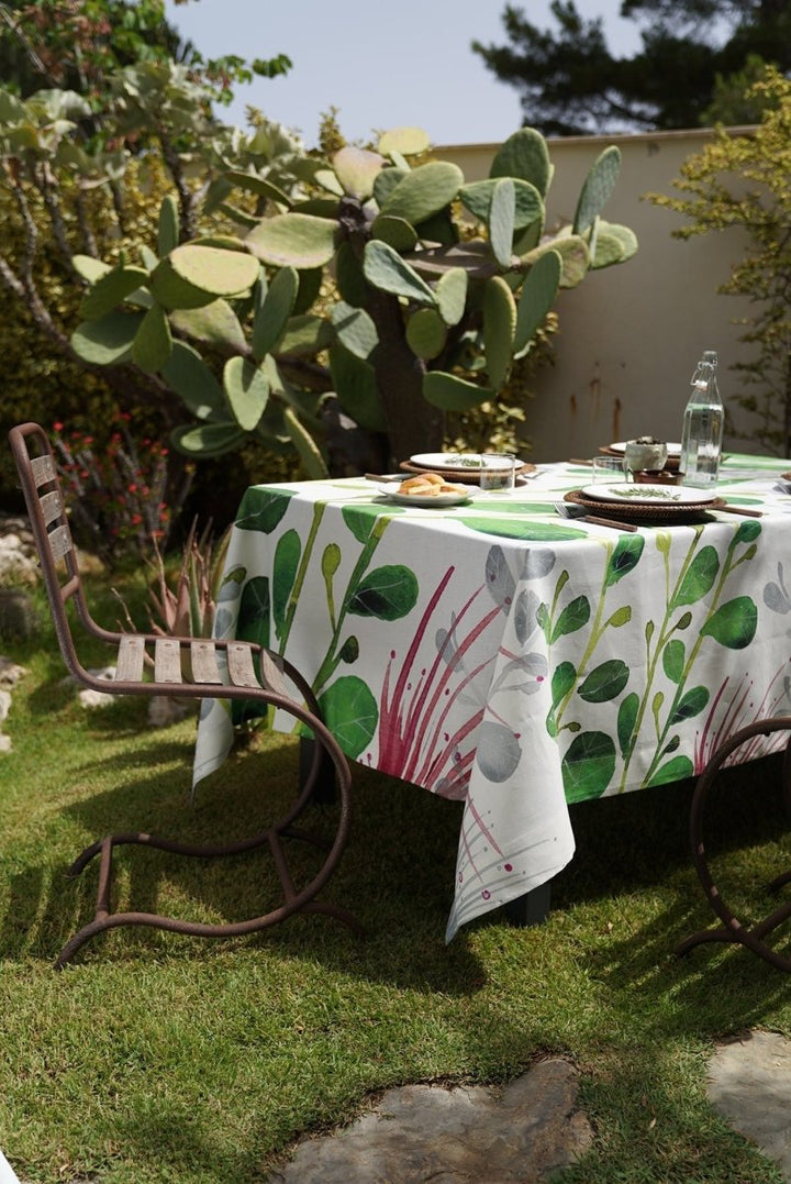 Outdoor setting with a tablecloth featuring green leaf patterns on a grassy area.
