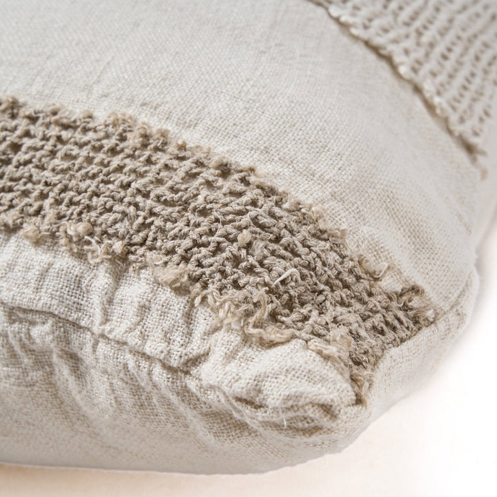 Textured fabric pillow with a frayed edge on a light background