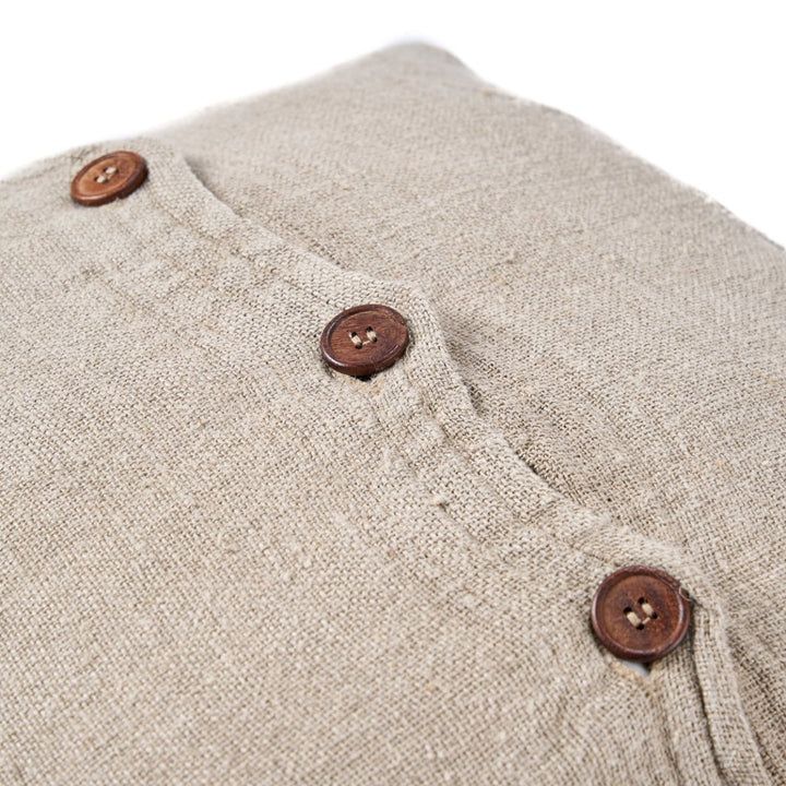 Close-up of beige fabric with brown buttons on a white background