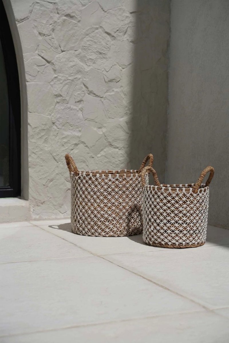 Two woven baskets with handles on a stone floor.