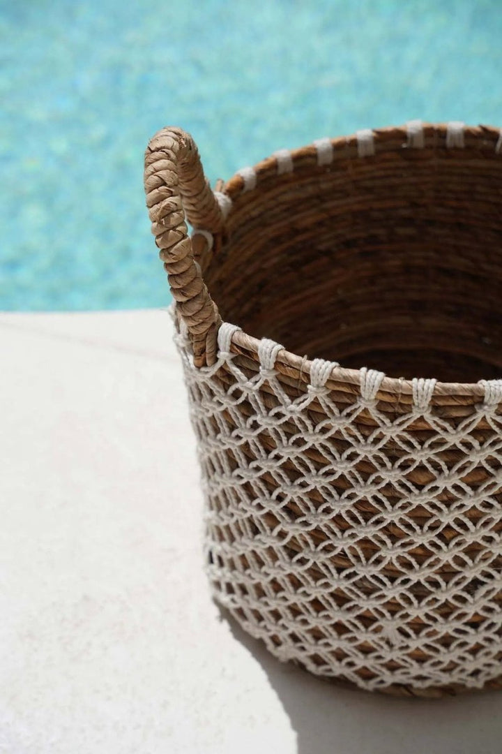 Woven basket with a textured handle on a white surface with a blue background