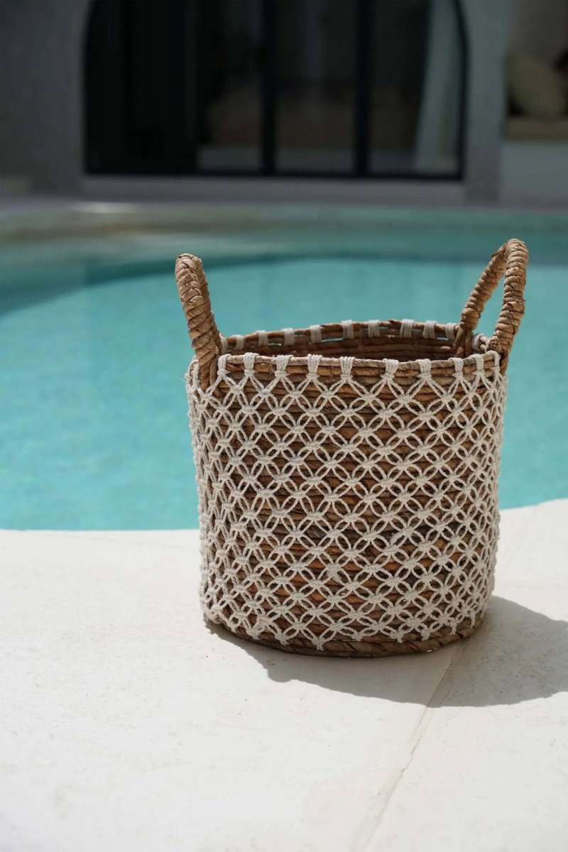 Woven basket with decorative pattern on a poolside surface