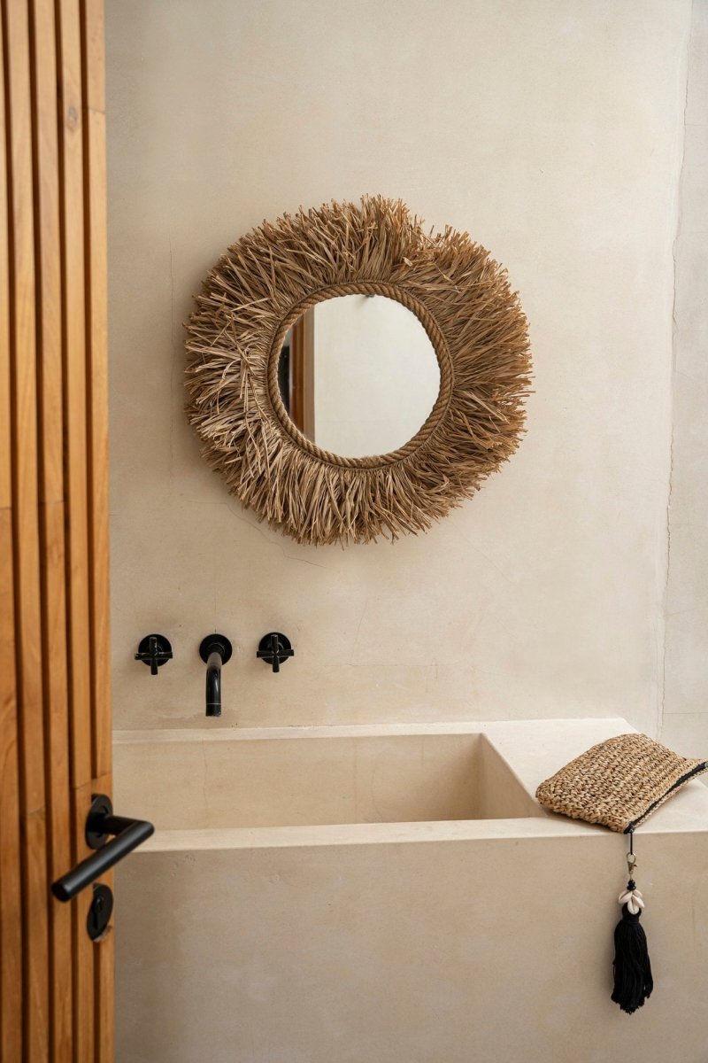 Bathroom with a round woven mirror above a bathtub.