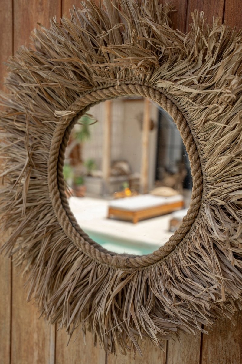 Round mirror with natural fiber frame on a wooden wall