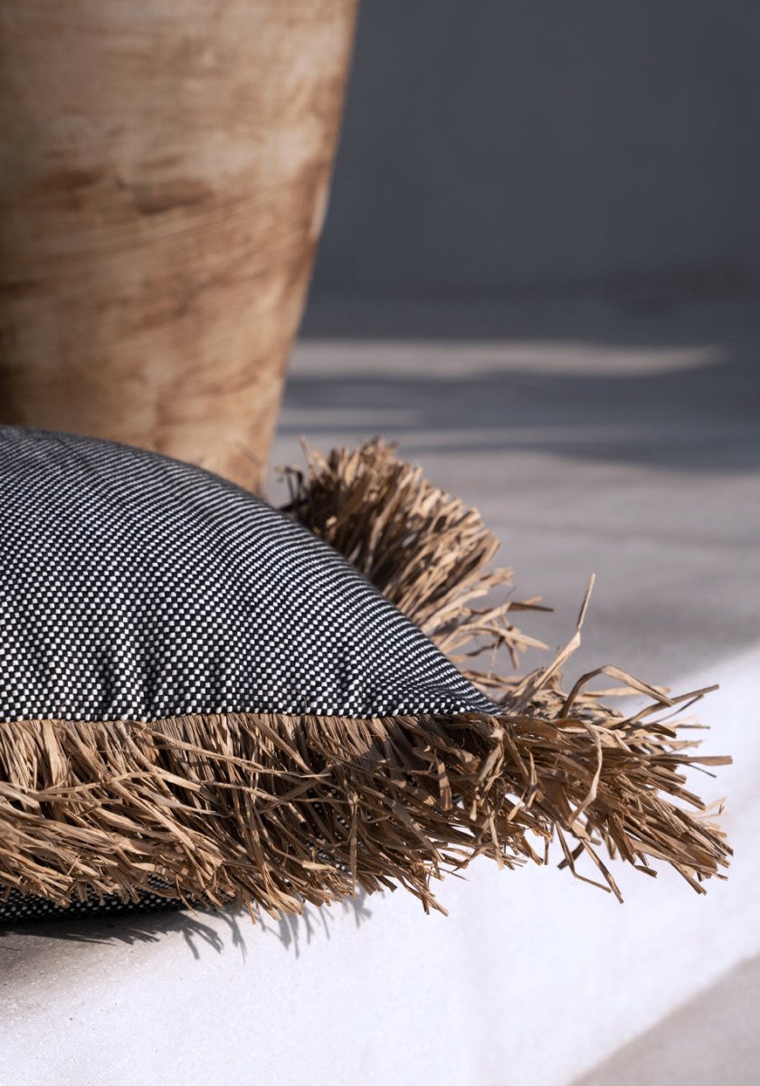 Textured pillow with frayed edge on a neutral background