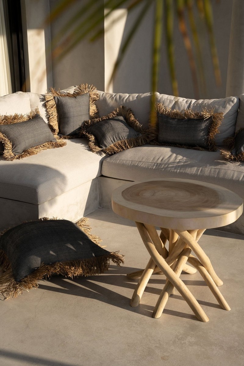 Outdoor seating area with a sectional sofa and round table on a concrete patio.