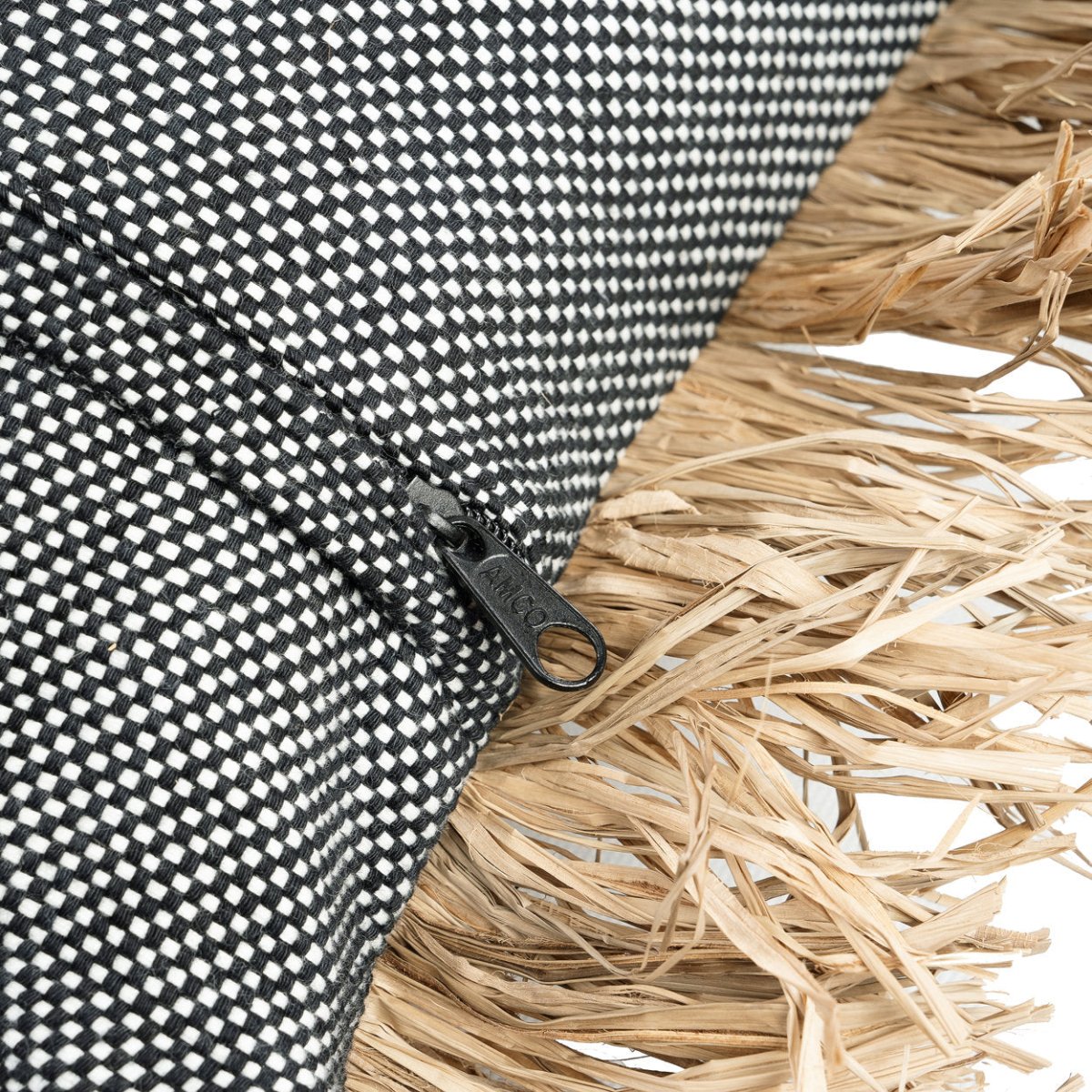Close-up of a black and white checkered fabric with a zipper and natural straw texture.