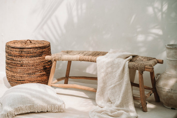 Woven basket, wooden stool, and textured rug against a white wall