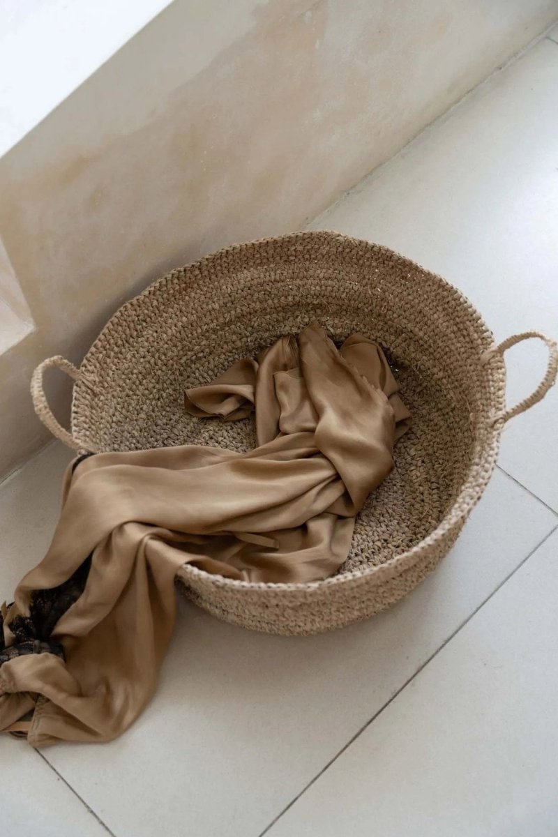 Woven basket with a beige cloth on a light-colored floor