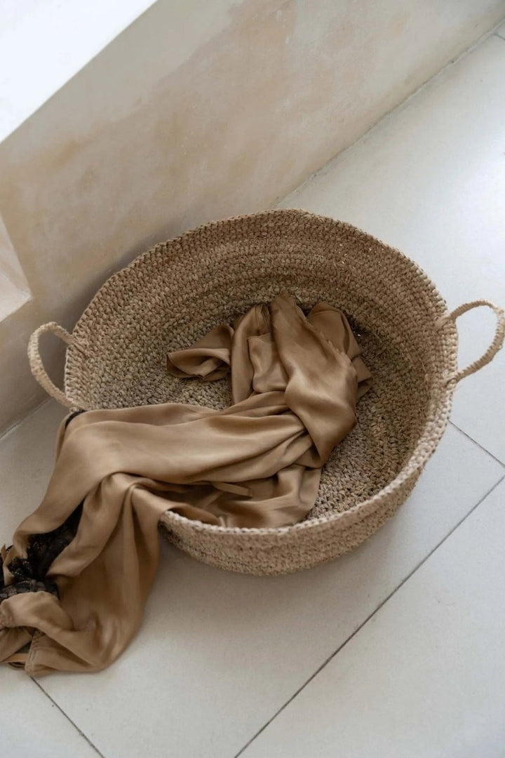 Woven basket with a beige cloth on a light-colored floor