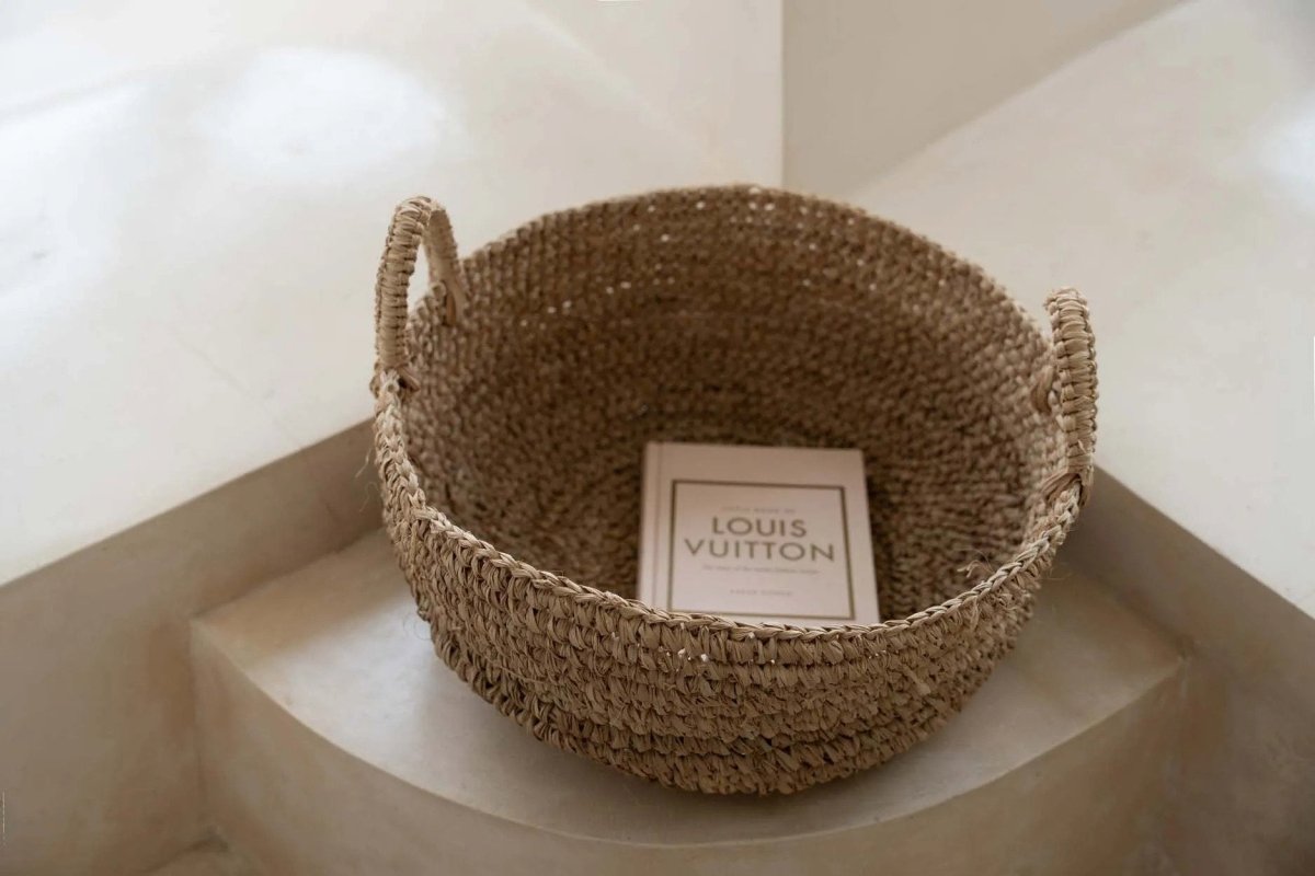 Woven basket with a Louis Vuitton box inside on a light surface