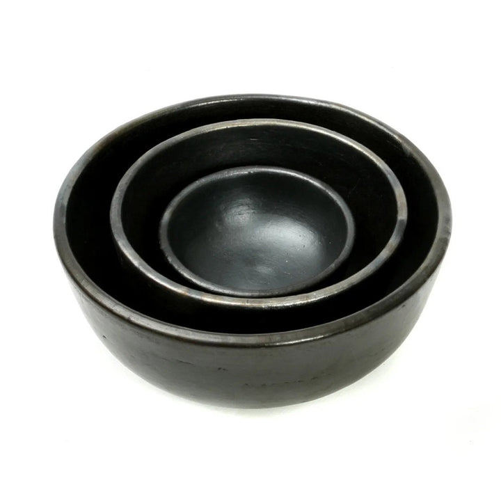 Set of three black ceramic bowls on a white background