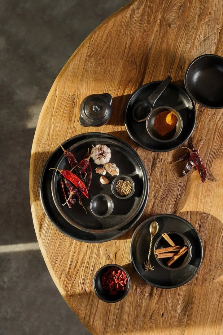 Black ceramic dishes with spices and ingredients on a wooden table