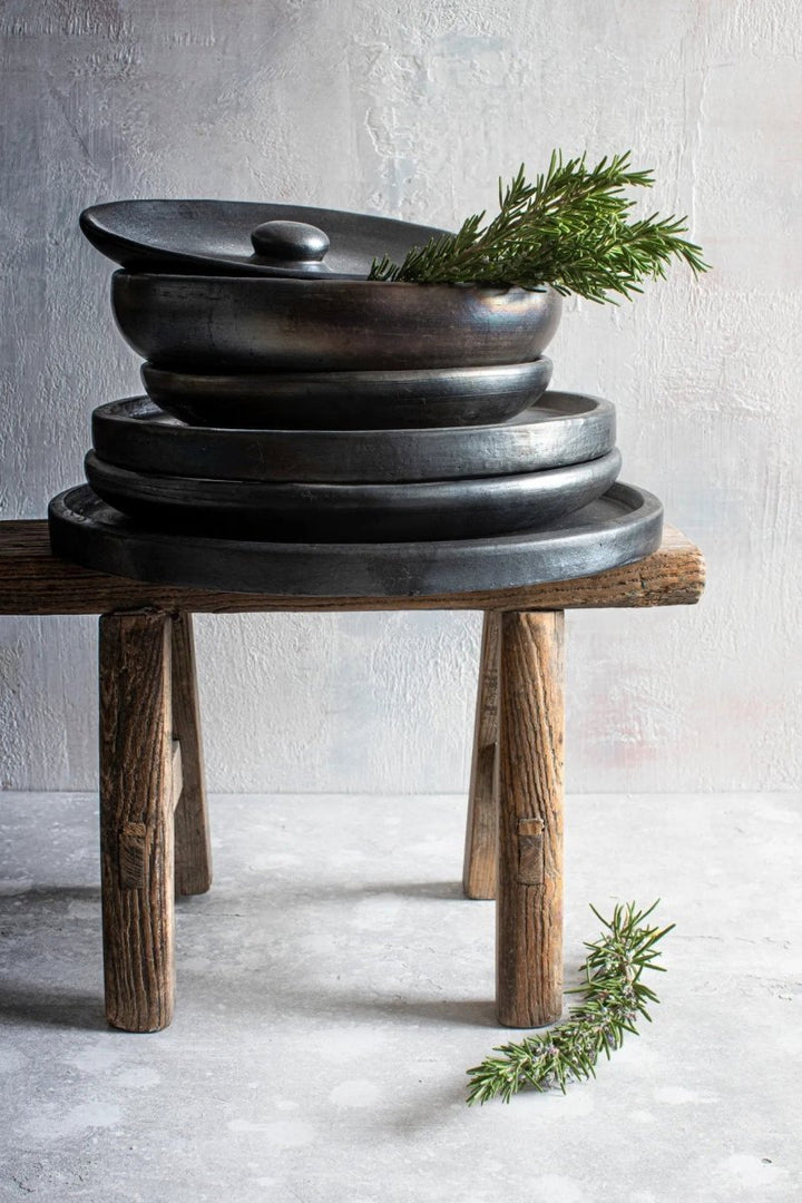 Set of black metal bowls on a wooden stand with a light gray background
