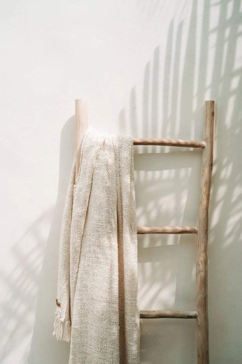 Wooden ladder with a beige blanket against a white wall