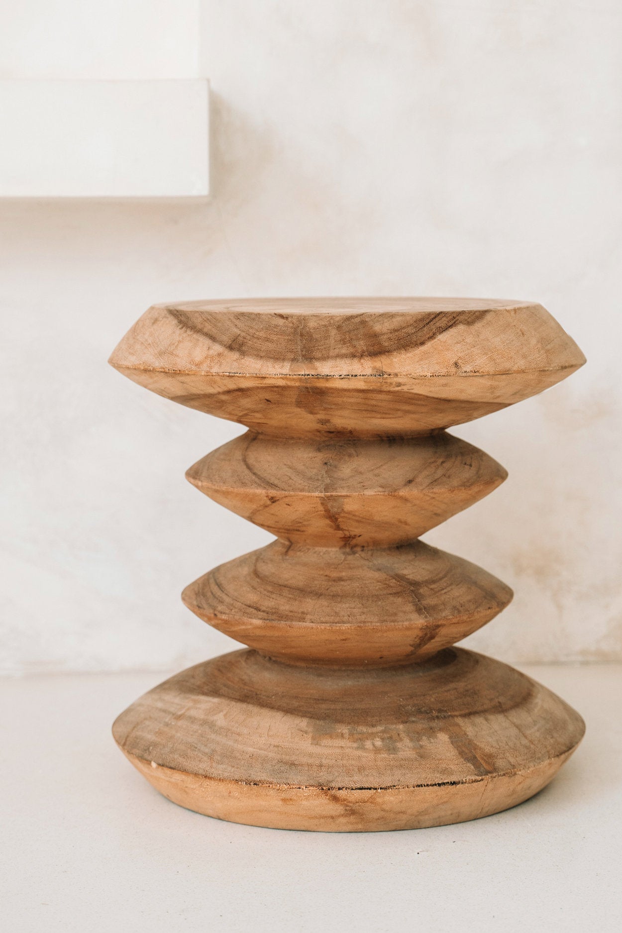 Wooden candle holder with stacked circular designs on a white background
