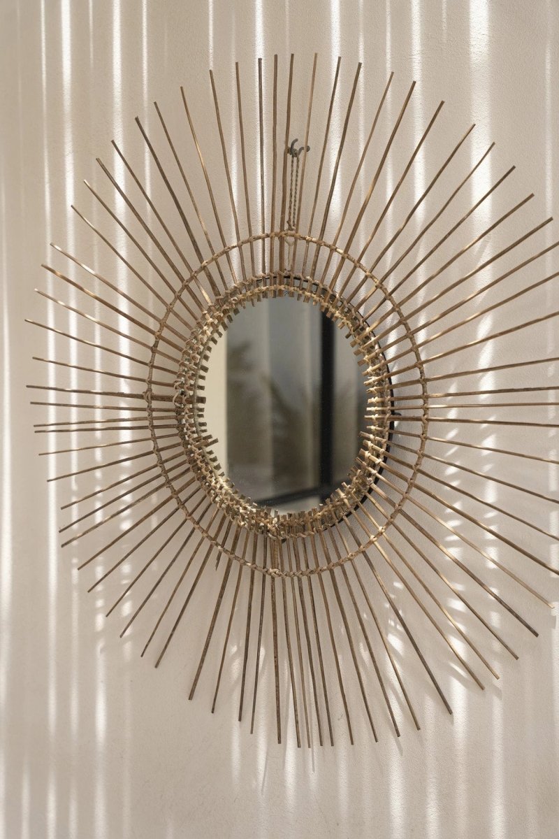 Decorative wall mirror with sunburst design on a white wall