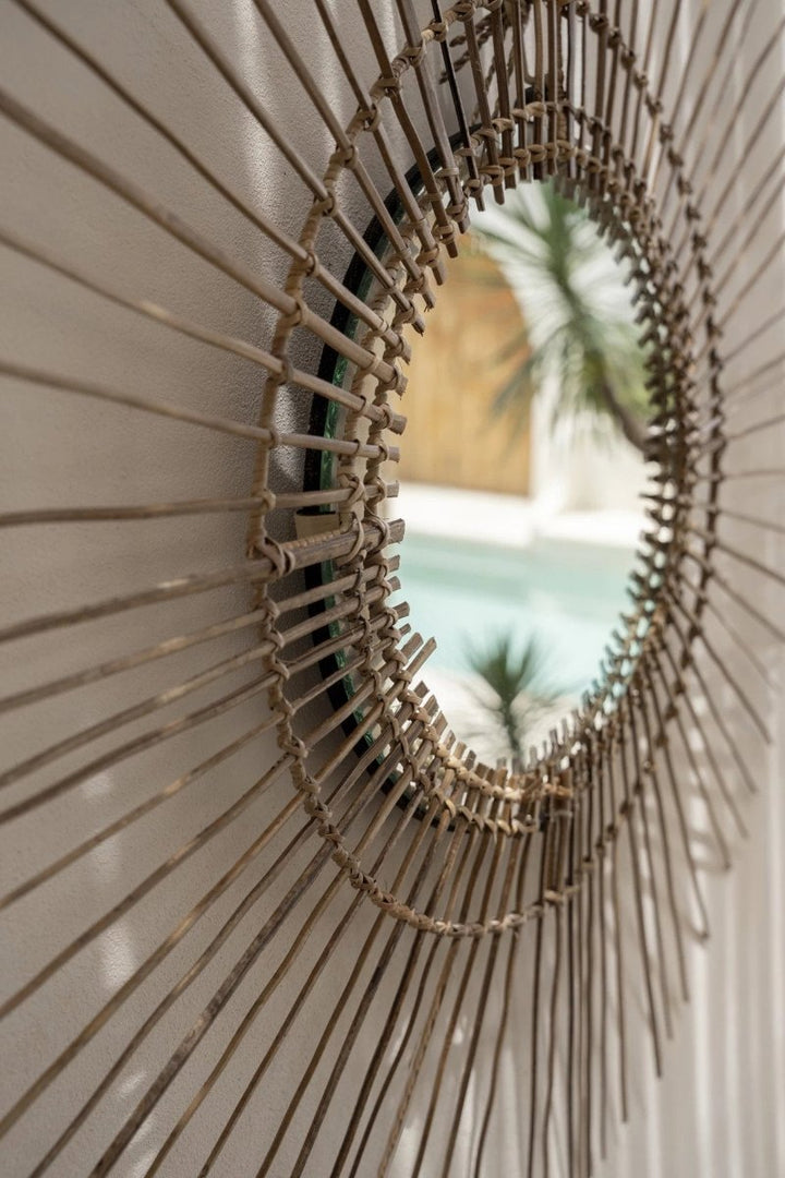 Round rattan mirror with blurred indoor background