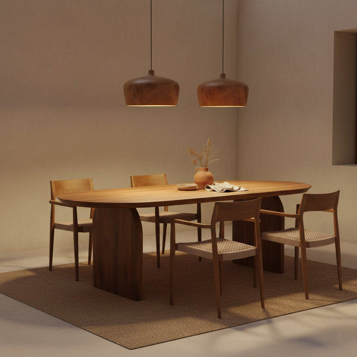 Dining area with wooden table and chairs under pendant lights in a warm-toned room.