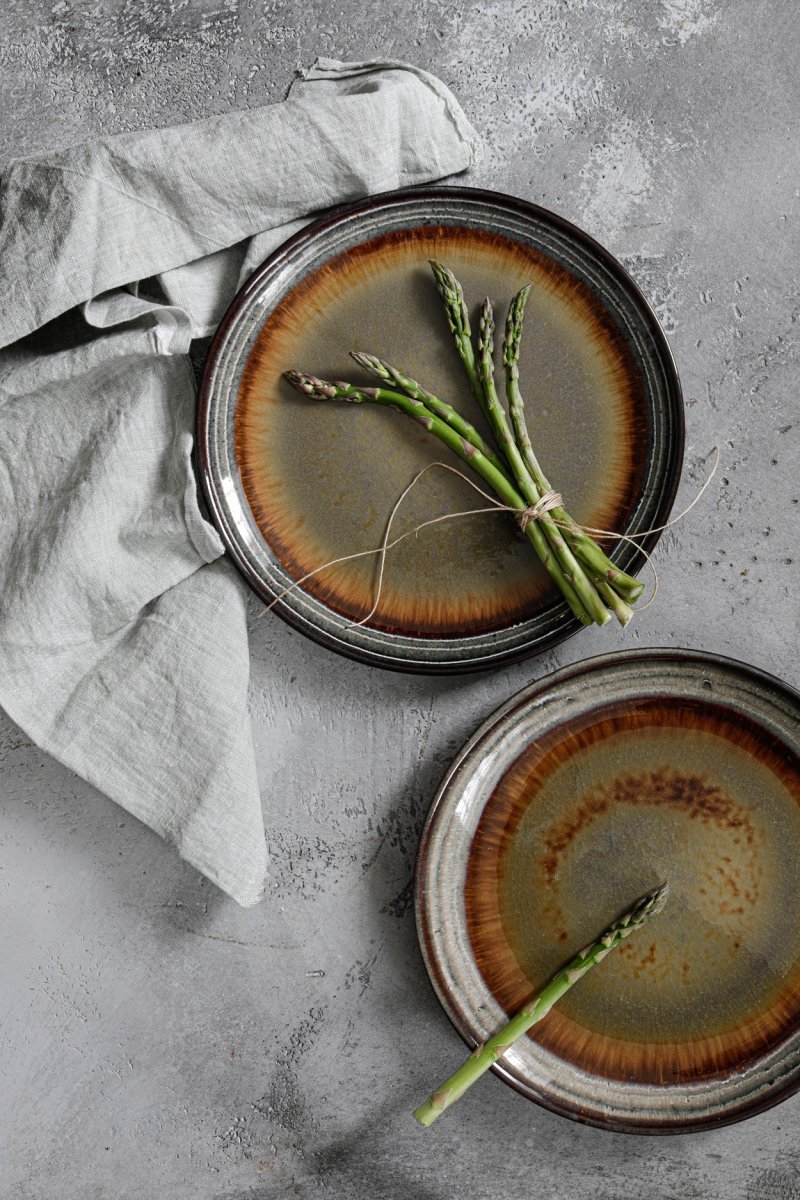 Two ceramic plates with asparagus on a gray surface