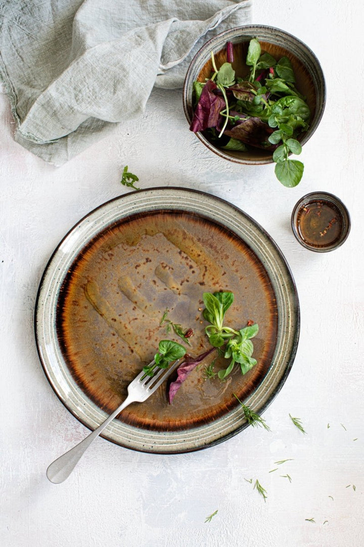 Dish with a brown sauce, fork, and garnishes on a white surface