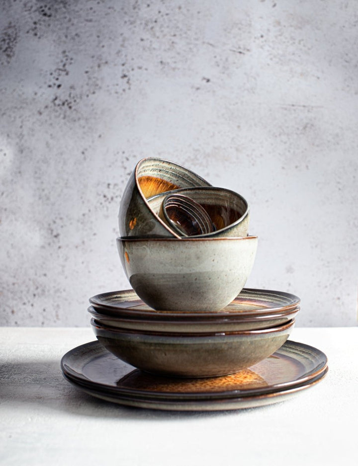 Stack of ceramic bowls and plates on a light surface with a gray textured background