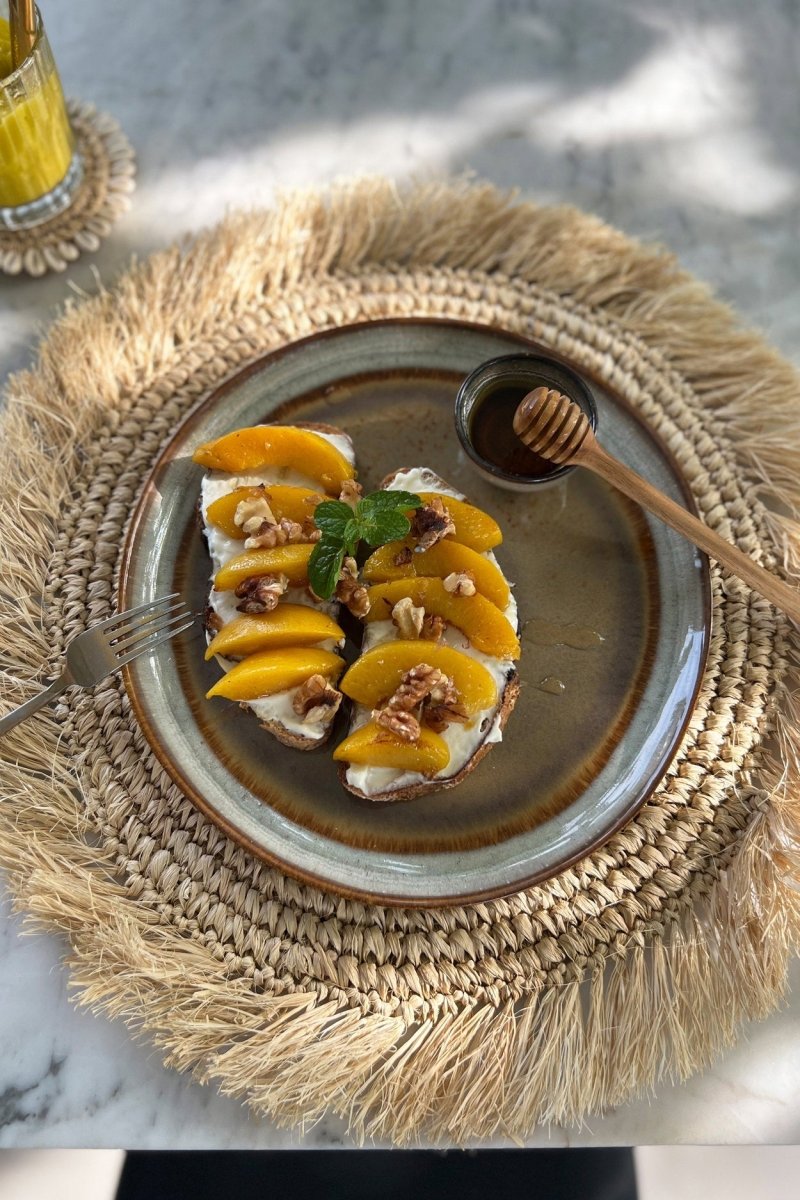 Plate of food with mango slices and nuts on a textured placemat