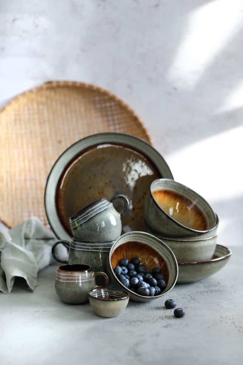 Set of ceramic dishes on a light surface with a woven mat in the background