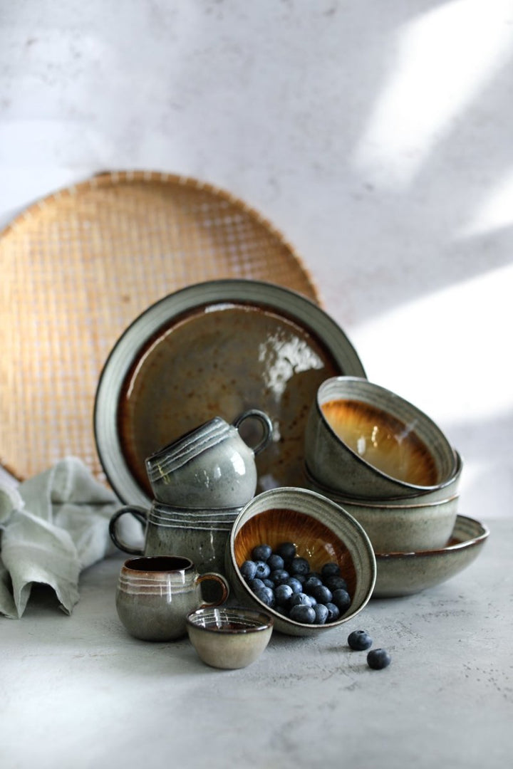 Set of ceramic dishes on a light surface with a woven mat in the background
