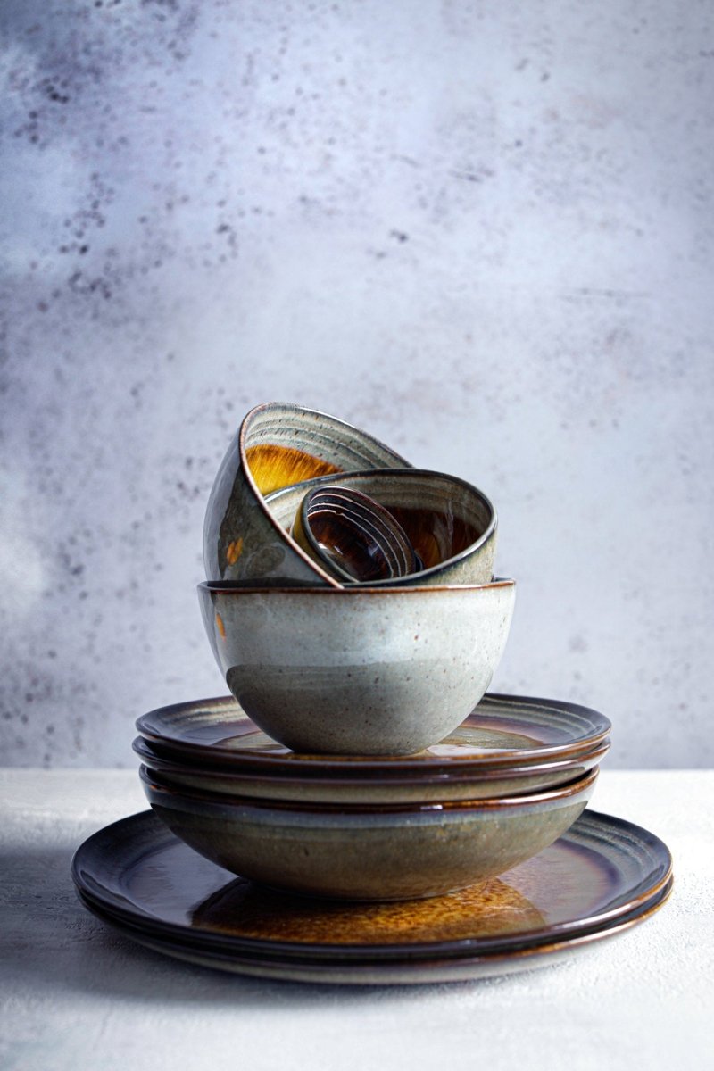 Stack of ceramic bowls with brown and gray glaze on a textured surface