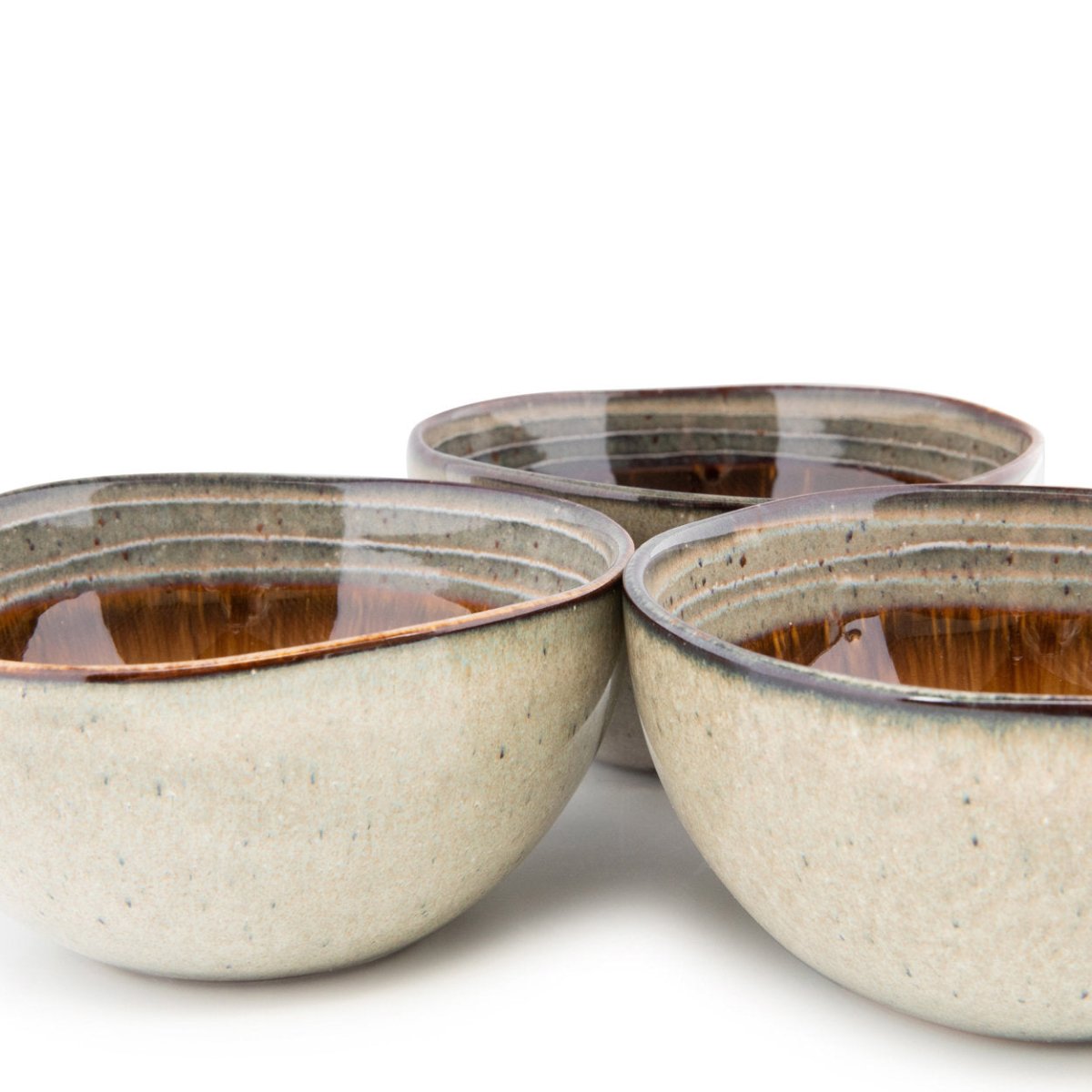 Three ceramic bowls with a speckled glaze on a white background