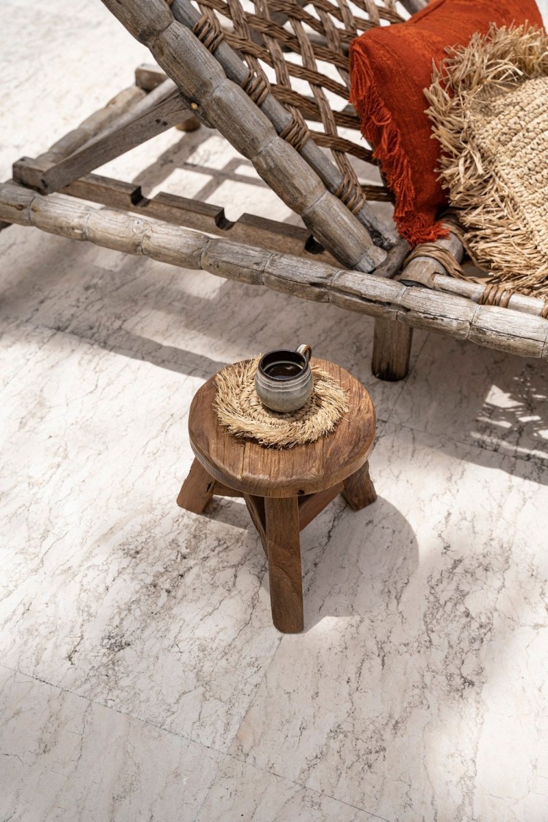 Wooden stool with a small table and decorative items on a marble floor