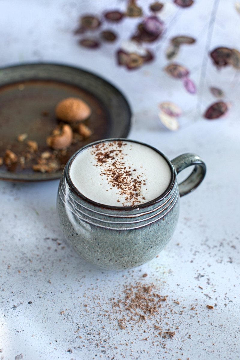 Mug of frothy beverage with cinnamon on a textured surface