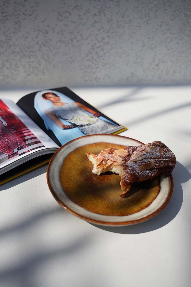 Dish with a piece of bread on a table next to an open magazine