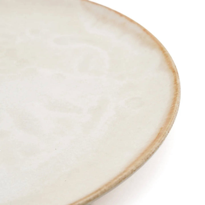 Close-up of a ceramic plate with a beige rim on a white background