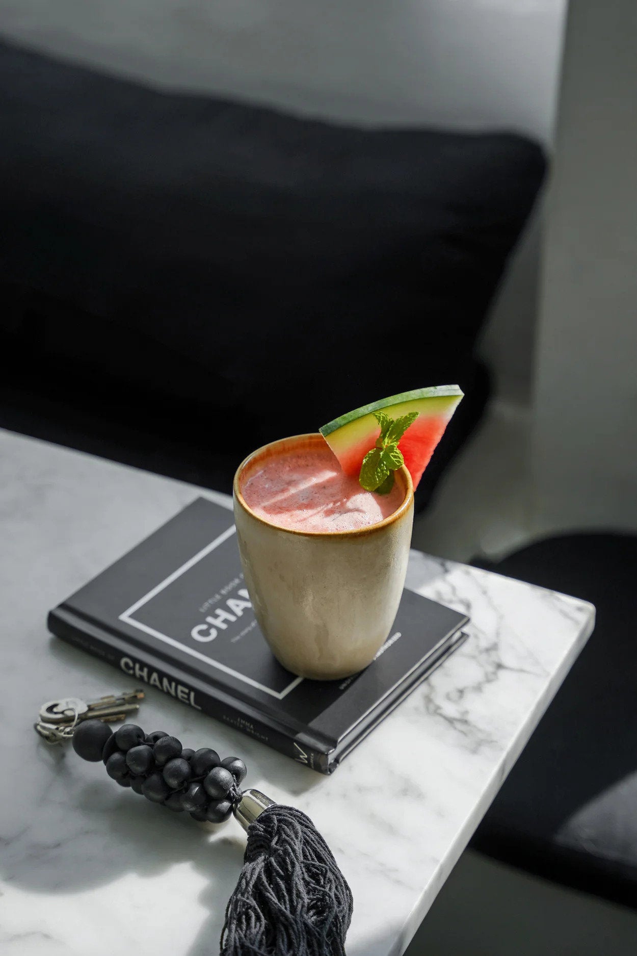 Mug with a slice of watermelon on a Chanel wallet on a marble surface