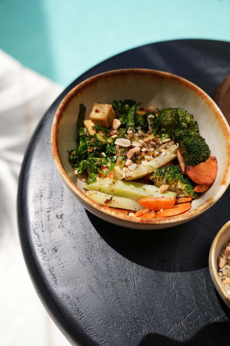 Bowl of vegetable stir-fry on a dark plate with a light background